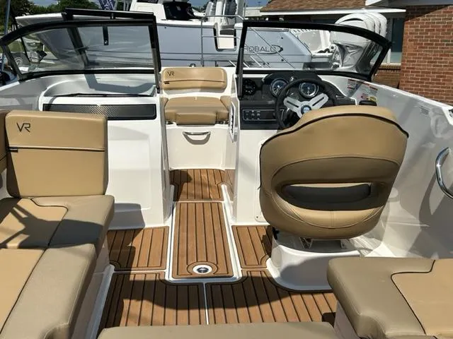 Slide: The Image of 2024 Bayliner VR4 boat interior with tan seats and wood flooring. - 11