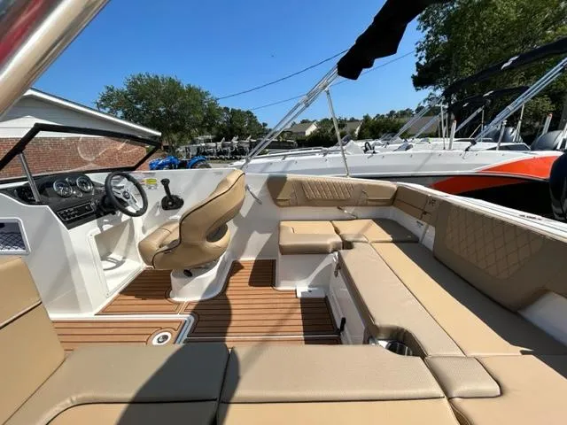 Slide: The Image of 2024 Bayliner VR4 boat interior with tan seating and wood flooring. - 12