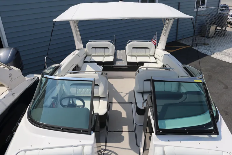 Slide: The Image of 2023 Regal LS6 boat with white seating and canopy, docked near a blue building. - 24