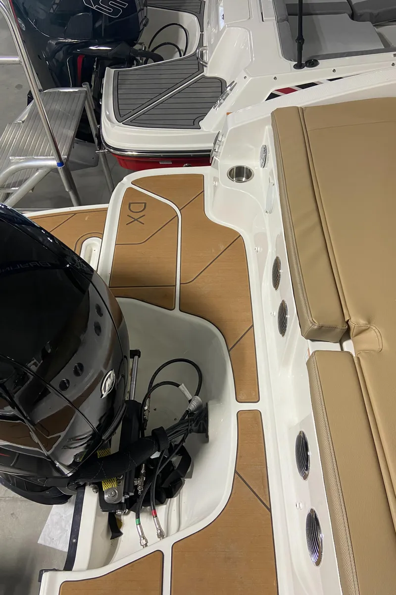 Slide: The Image of 2024 Bayliner DX2000 boat interior with tan seating and outboard motor. - 7