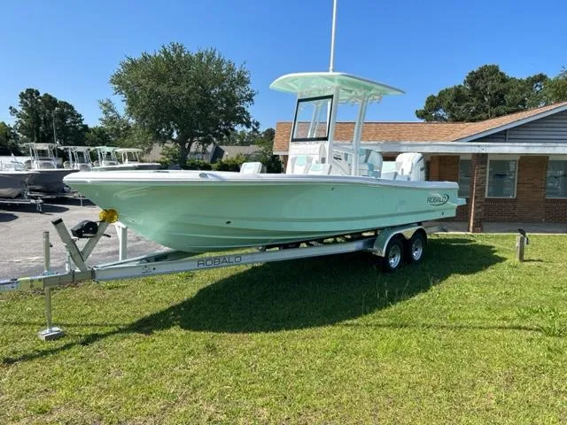 Slide: The Image of 2024 Robalo 246 Cayman boat on a trailer, parked on grass. - 2