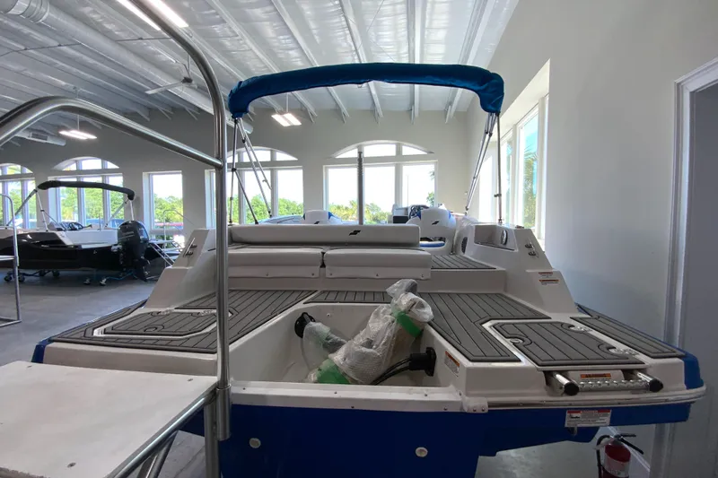 Slide: The Image of 2024 Starcraft SVX 231 boat in showroom, rear view with blue canopy. - 3