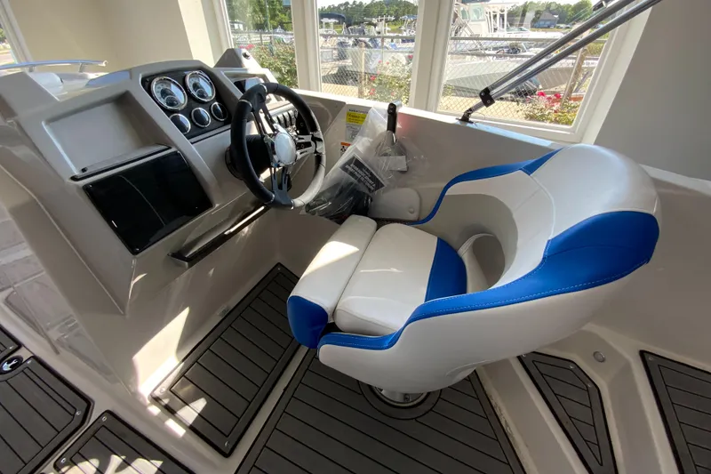 Slide: The Image of 2024 Starcraft SVX 231 boat cockpit with steering wheel and captain's chair. - 9