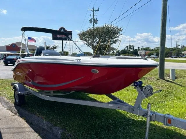 Slide: The Image of 2024 Bayliner Element M17 boat on a trailer, red hull, parked outdoors. - 1