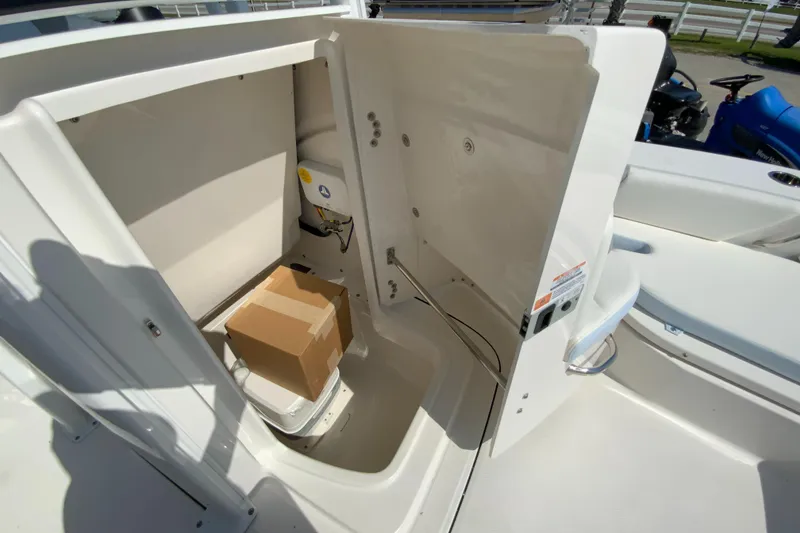 Slide: The Image of 2024 Robalo 246 Cayman storage compartment with a cardboard box inside. - 27