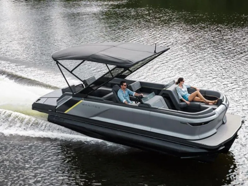 Slide: The Image of 2023 Manitou Explore pontoon boat cruising on a lake. - 0