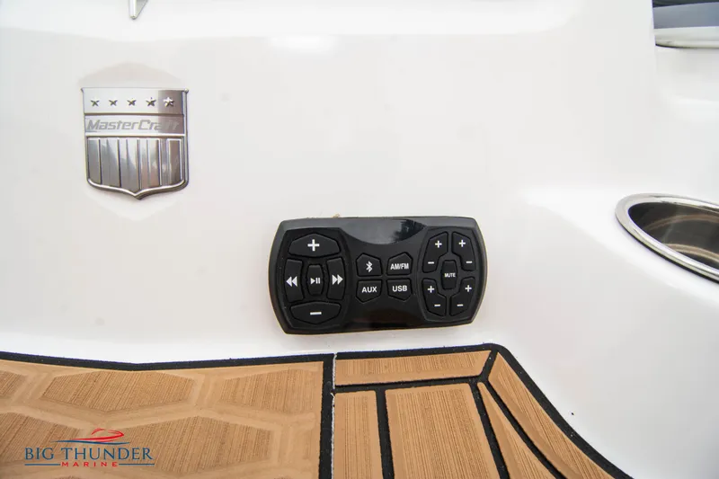 Slide: The Image of 2023 MasterCraft X24 boat control panel and logo on teak flooring. - 13