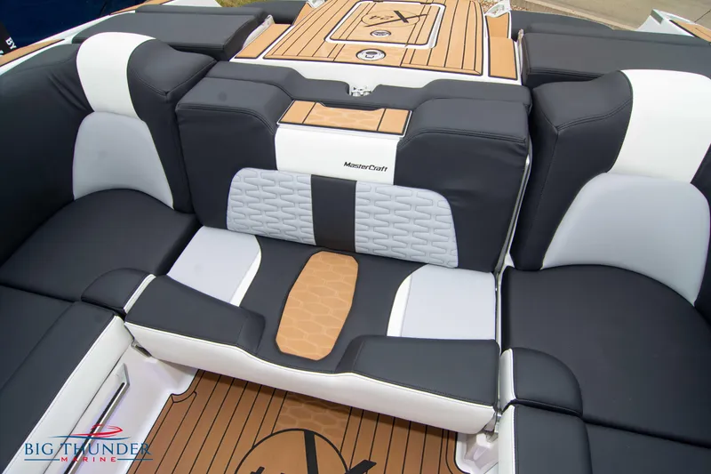 Slide: The Image of 2023 MasterCraft X24 boat interior with black and white seating and teak flooring. - 23