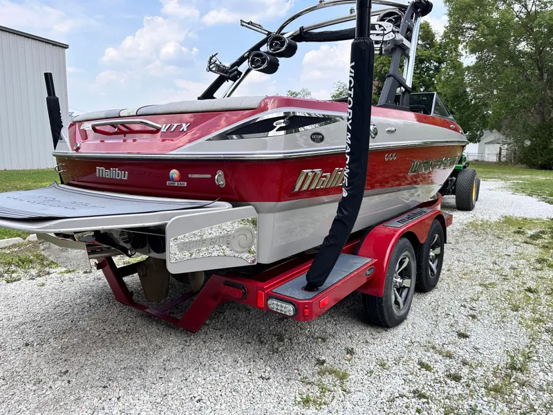 Slide: The Image of 2014 Malibu VTX WAKESETTER boat on a red trailer, parked on gravel. - 3