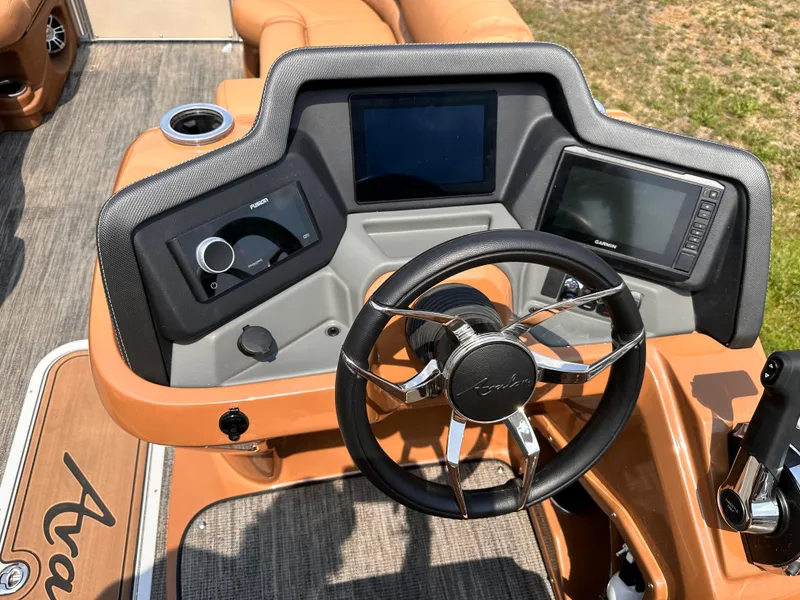 Slide: The Image of 2023 Avalon Catalina Quad Lounger 25 dashboard with steering wheel and navigation screens. - 8