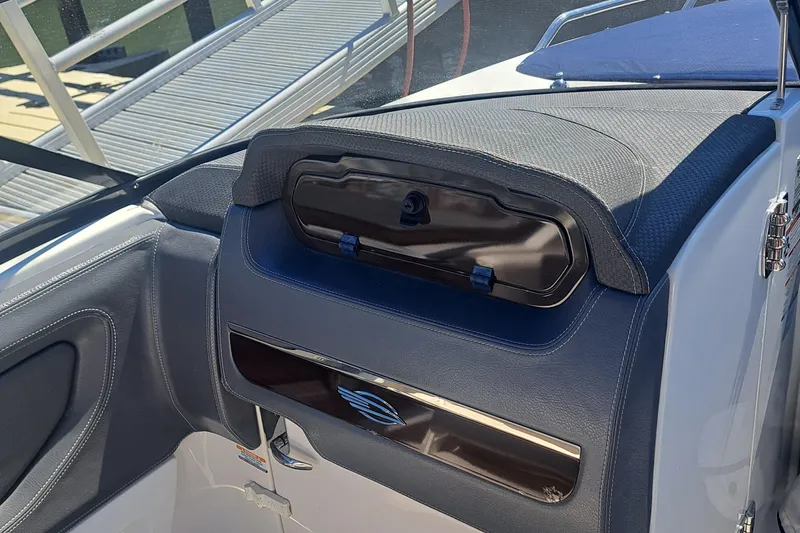 Slide: The Image of 2018 Chaparral 257 SSX boat dashboard with storage compartment, dockside view. - 29