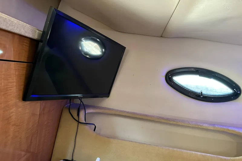 Slide: The Image of 2003 Regal 3260 Commodore cabin interior with mounted TV and porthole window. - 21