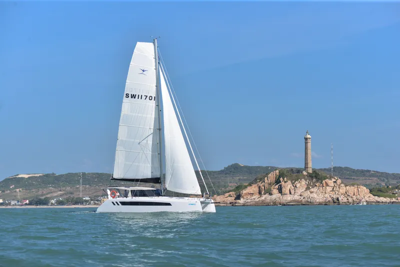 Slide: The Image of 2025 Seawind 1170 sailing near a rocky coastline with a lighthouse. - 11