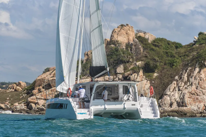 Slide: The Image of 2025 Seawind 1170 catamaran sailing near rocky coastline. - 12