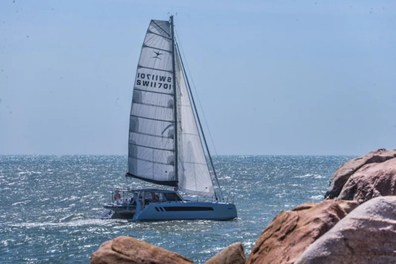 Slide: The Image of 2025 Seawind 1170 sailing near rocky coastline on a sunny day. - 13
