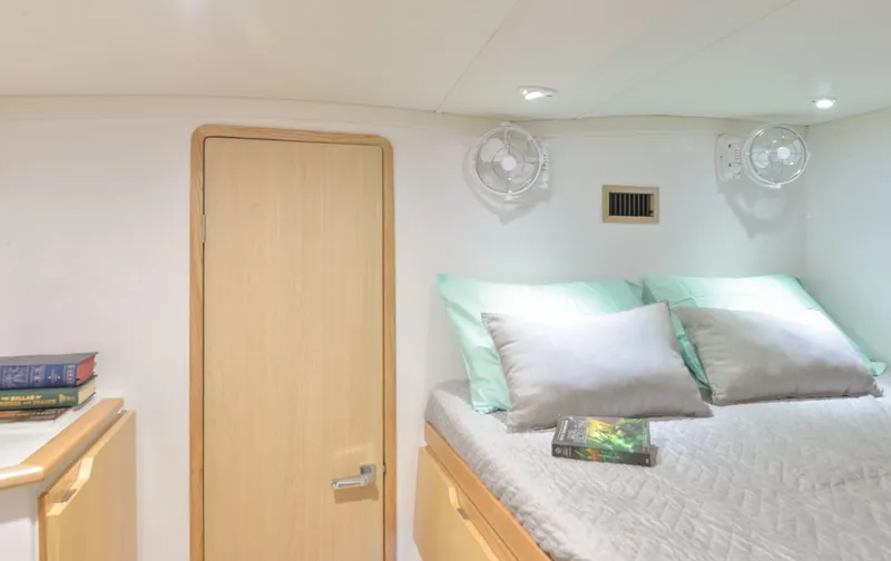 Slide: The Image of Seawind 1170 2025 model cabin with bed, pillows, book, and wooden door. - 28