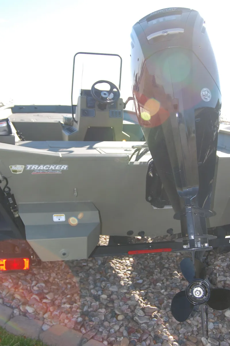 Slide: The Image of 2023 Tracker Grizzly 2072 CC boat with outboard motor on rocky ground. - 2