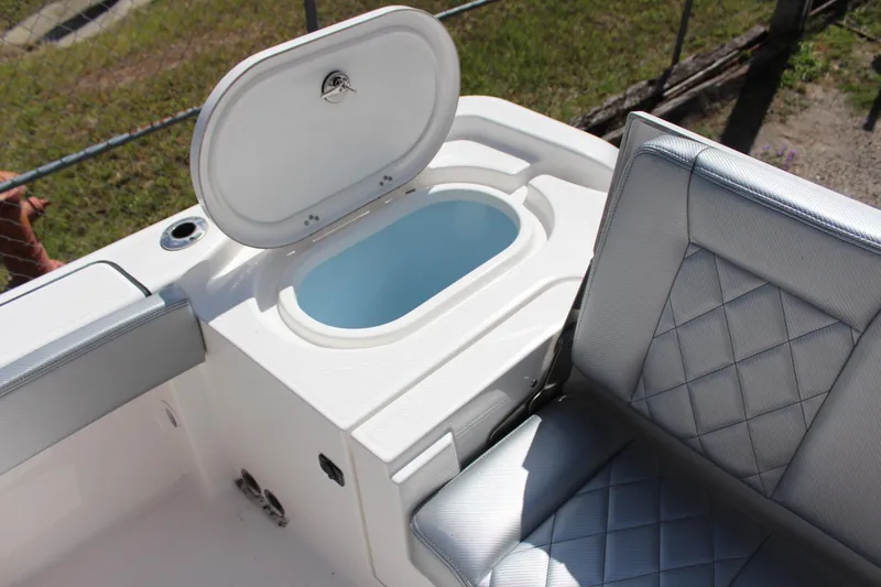 Slide: The Image of 2023 Blue Wave 2600 Makaira boat with open storage compartment and cushioned seating. - 17