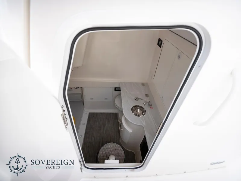 Slide: The Image of 2023 Regulator 34 yacht interior bathroom view with sink and toilet. Sovereign Yachts logo. - 12