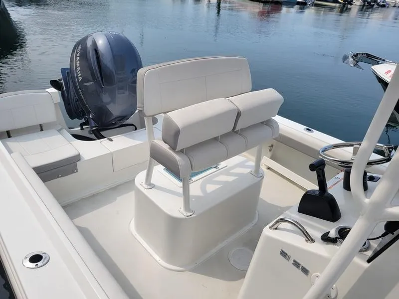 Slide: The Image of 2023 Parker 2100 SE boat interior with seating and motor, docked on calm water. - 5