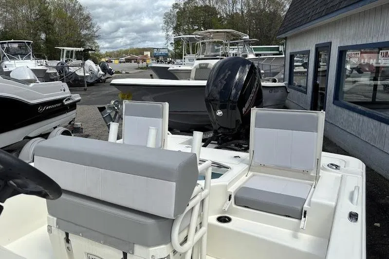 Slide: The Image of 2023 Mako SKIFF 19 CC boat with seating and outboard motor in a marina. - 16