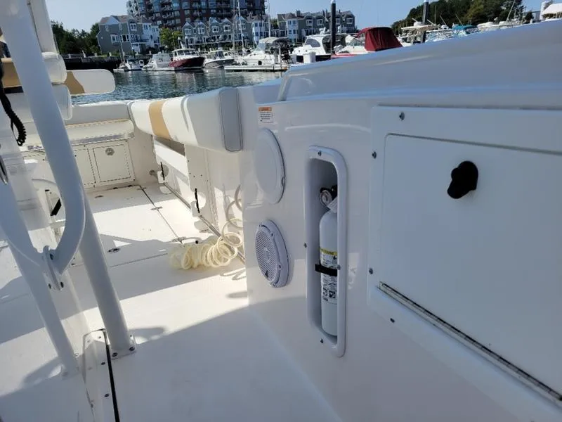Slide: The Image of 2023 Edgewater 245 CC boat interior with seating, storage, and safety equipment at a marina. - 2