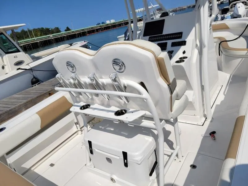 Slide: The Image of 2023 Edgewater 245 CC boat interior with seating and console, docked by the water. - 3