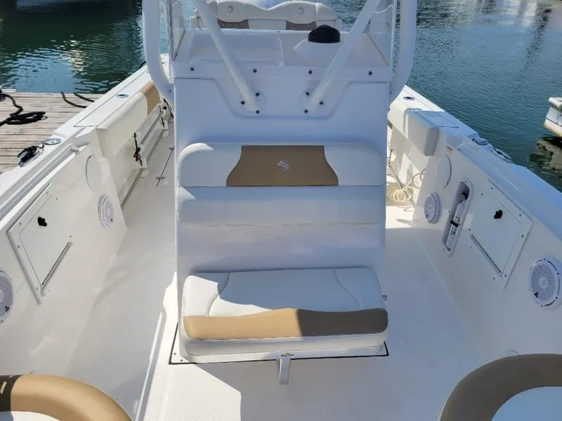 Slide: The Image of 2023 Edgewater 245 CC boat interior with seating and console, docked by the water. - 5