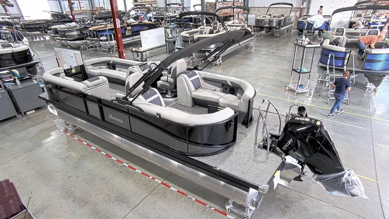 Slide: The Image of 2024 Barletta C24QC pontoon boat in a showroom, featuring sleek design and spacious seating. - 2