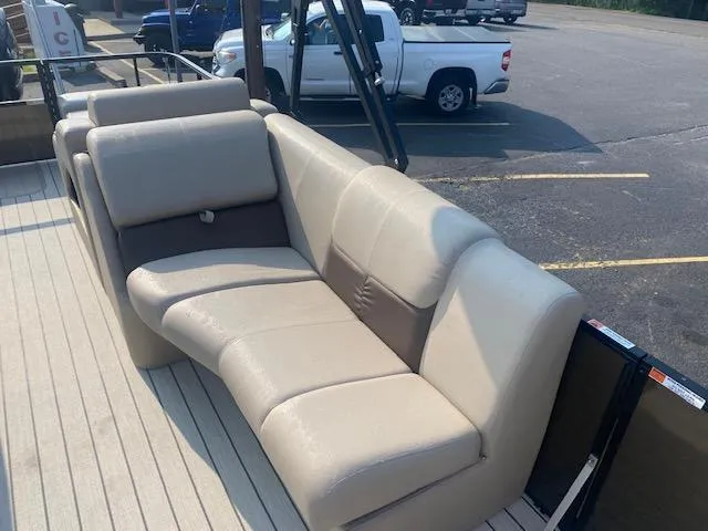 Slide: The Image of 2023 SunCatcher Fusion 324SS boat interior with beige seating in a parking lot. - 13