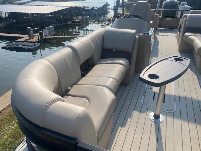 Slide: The Image of 2023 SunCatcher Fusion 324SS pontoon boat with beige seating and table, docked by the water. - 4