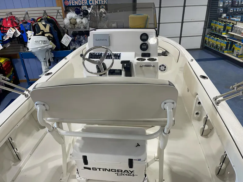 Slide: The Image of 2023 Stingray 173CC boat interior with steering console and seating, displayed in a showroom. - 11