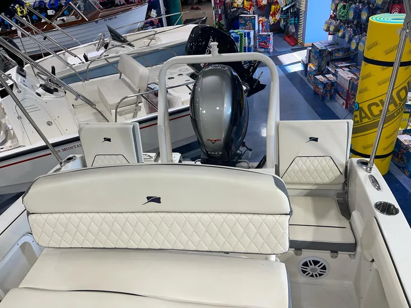Slide: The Image of 2023 Stingray 173CC boat interior with white seating and motor, displayed in a showroom. - 13