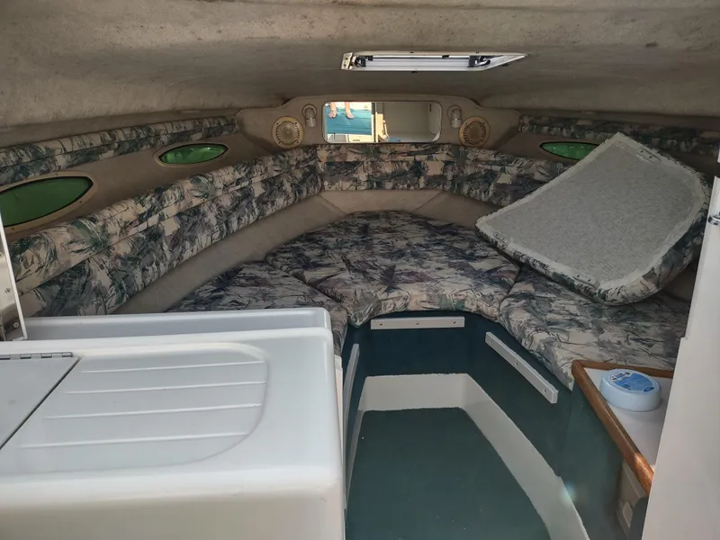 Slide: The Image of Interior of 1997 Sea Ray 240 SIGNATURE boat with cushioned seating and small kitchenette. - 16