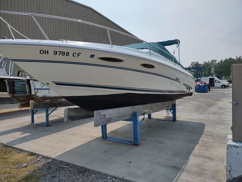 Slide: The Image of 1997 Sea Ray 240 SIGNATURE boat on stands, outdoor storage, side view. - 2