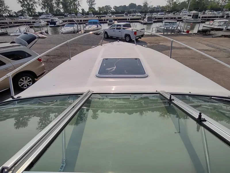 Slide: The Image of 1997 Sea Ray 240 Signature boat docked at marina with cars and boats in background. - 5
