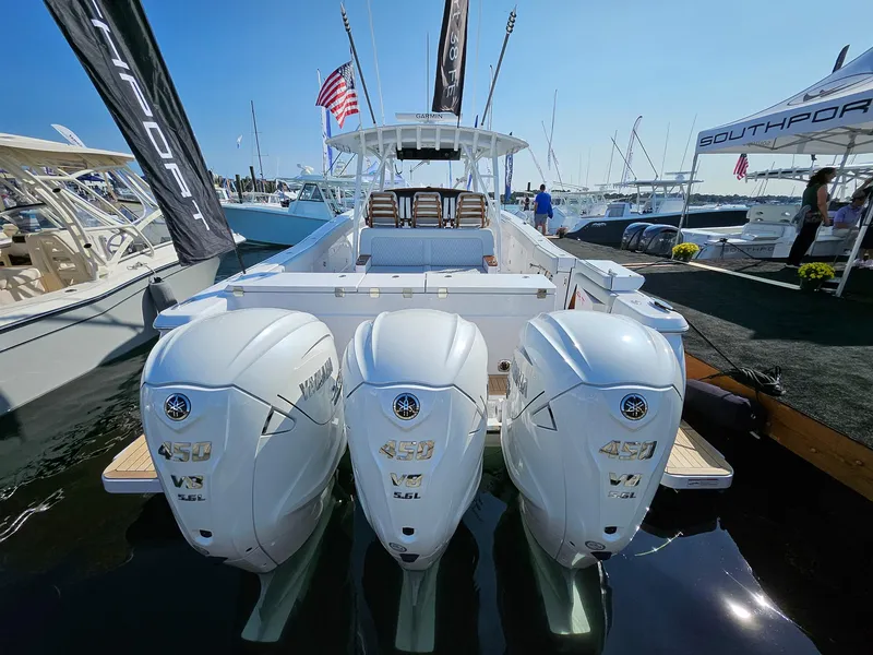 Slide: The Image of 2025 Southport 38 FE boat with triple outboard engines at a marina display. - 1