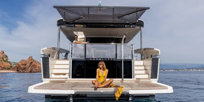 Slide: The Image of 2025 Absolute NAVETTA 75 yacht with people relaxing on deck, scenic ocean backdrop. - 6