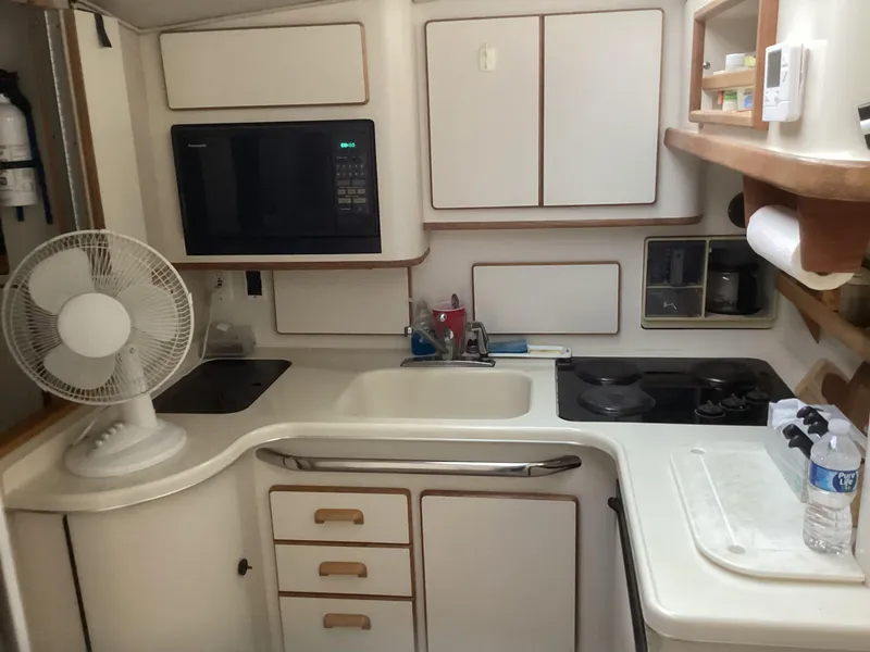 Slide: The Image of Compact kitchen area in a 1994 Sea Ray 370 Sedan Bridge yacht, featuring a microwave and stove. - 14