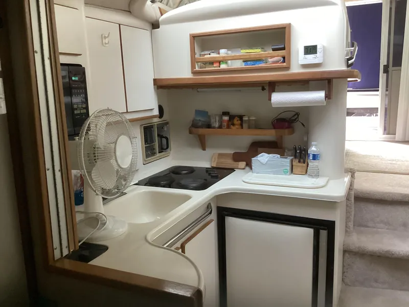 Slide: The Image of 1994 Sea Ray 370 Sedan Bridge kitchen area with stove, sink, and storage shelves. - 15