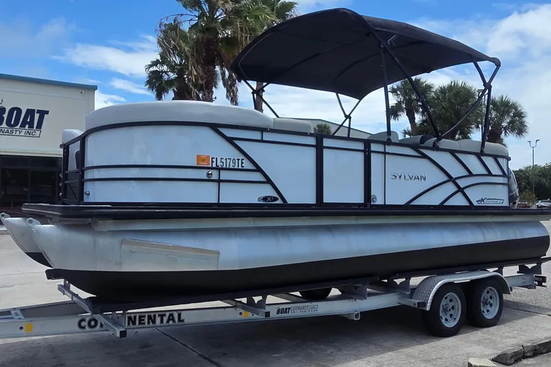 Slide: The Image of 2022 Sylvan Mirage X X3 pontoon boat on trailer, parked outdoors. - 11