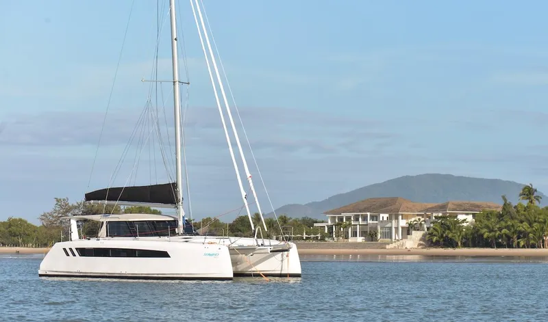 Slide: The Image of 2025 Seawind 1170 catamaran sailing near a coastal villa with mountains in the background. - 10