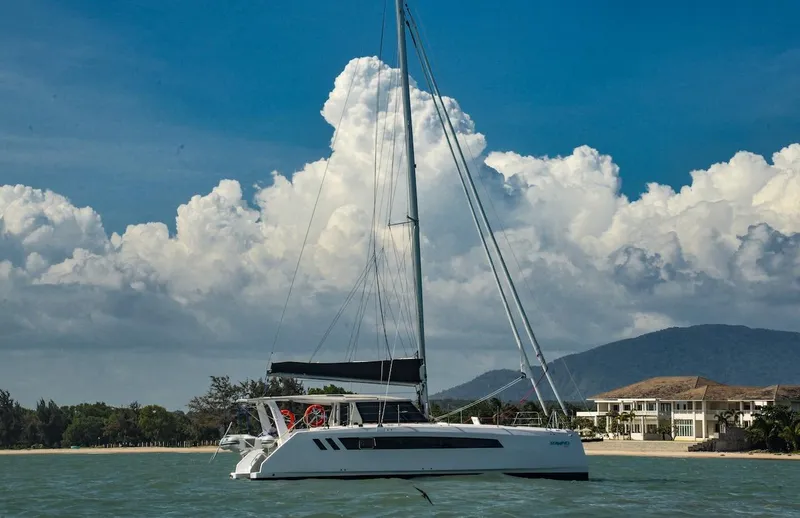 Slide: The Image of 2025 Seawind 1170 catamaran sailing near a scenic coastline with mountains and clouds. - 11