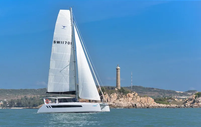 Slide: The Image of 2025 Seawind 1170 catamaran sailing near a coastal lighthouse. - 14