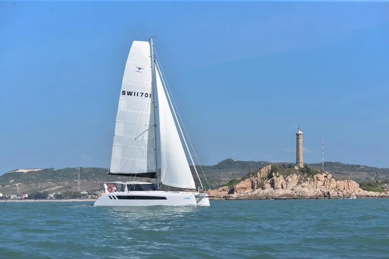 Slide: The Image of 2025 Seawind 1170 catamaran sailing near a rocky coastline with a lighthouse. - 16
