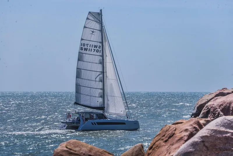 Slide: The Image of 2025 Seawind 1170 catamaran sailing near rocky coastline on a sunny day. - 21