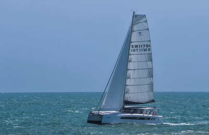 Slide: The Image of 2025 Seawind 1170 catamaran sailing on open sea under clear blue sky. - 23