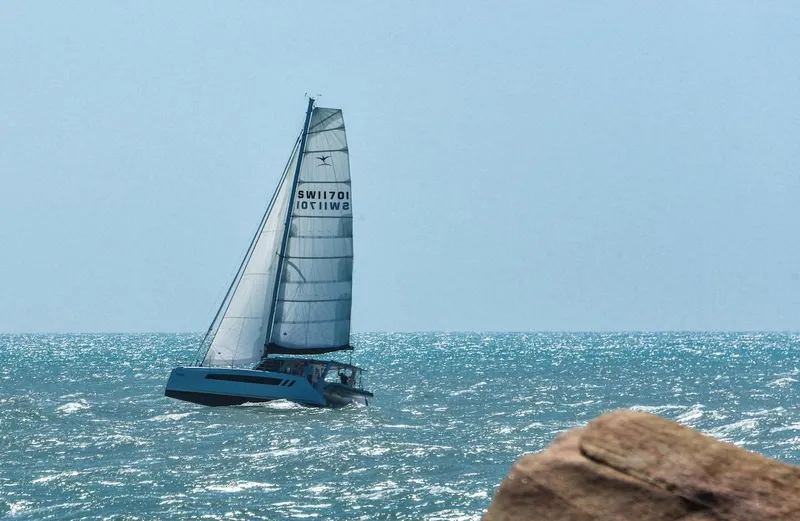 Slide: The Image of 2025 Seawind 1170 catamaran sailing on open sea near rocky shore. - 28
