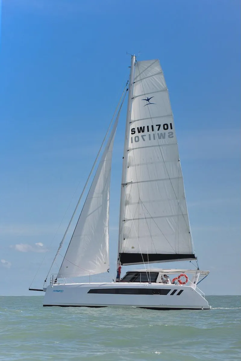 Slide: The Image of 2025 Seawind 1170 catamaran sailing on open water under clear blue skies. - 42