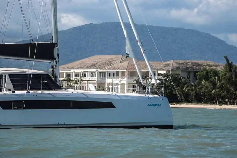 Slide: The Image of 2025 Seawind 1170 catamaran sailing near tropical resort with mountain backdrop. - 6